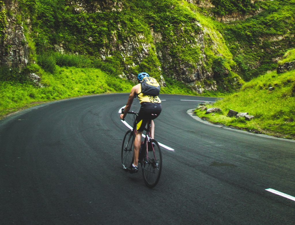 cyclist biking through luscious green mountain