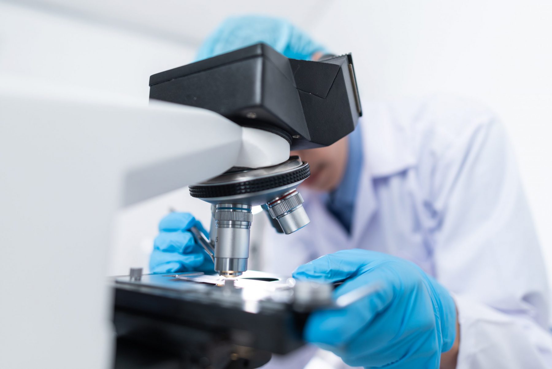 A scientist examines a slide under a microscope