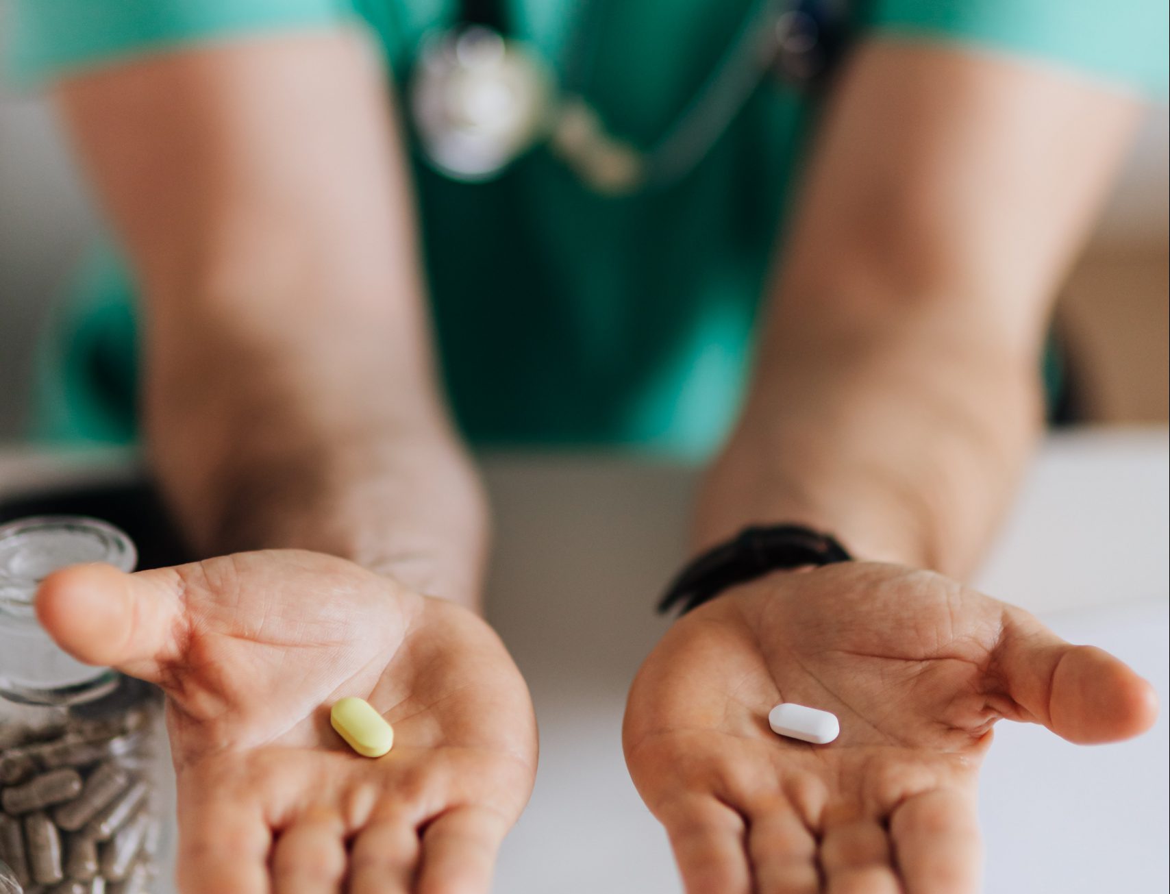 doctor hands reaching out with two different pills on either palm