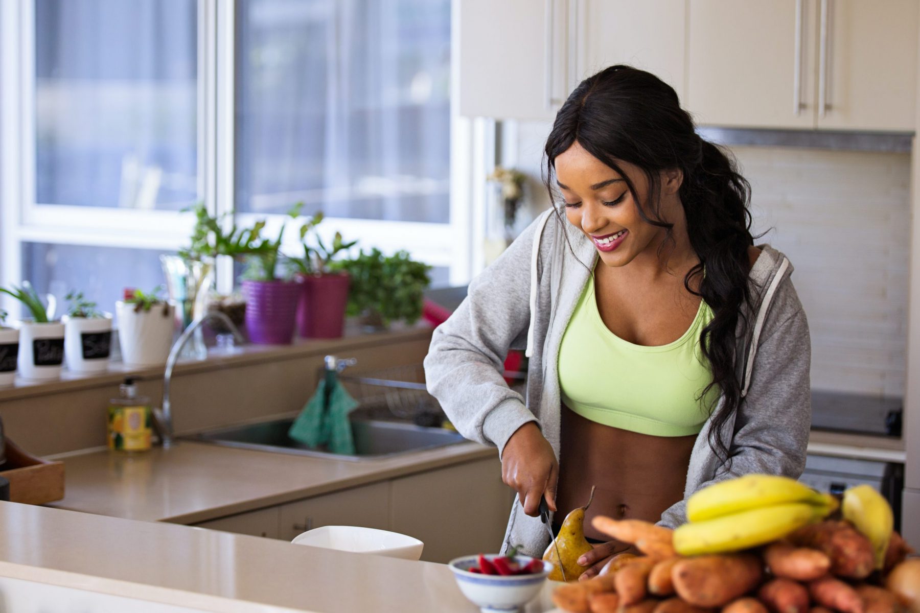 Women in kitchen smiling and cutting fruit