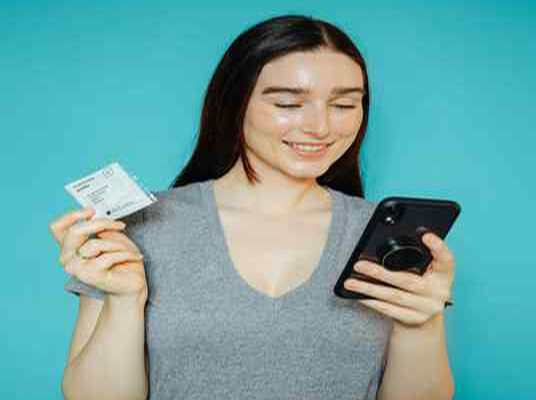 Woman looking at her phone while holding an Autumn DNA customized vitamin packet